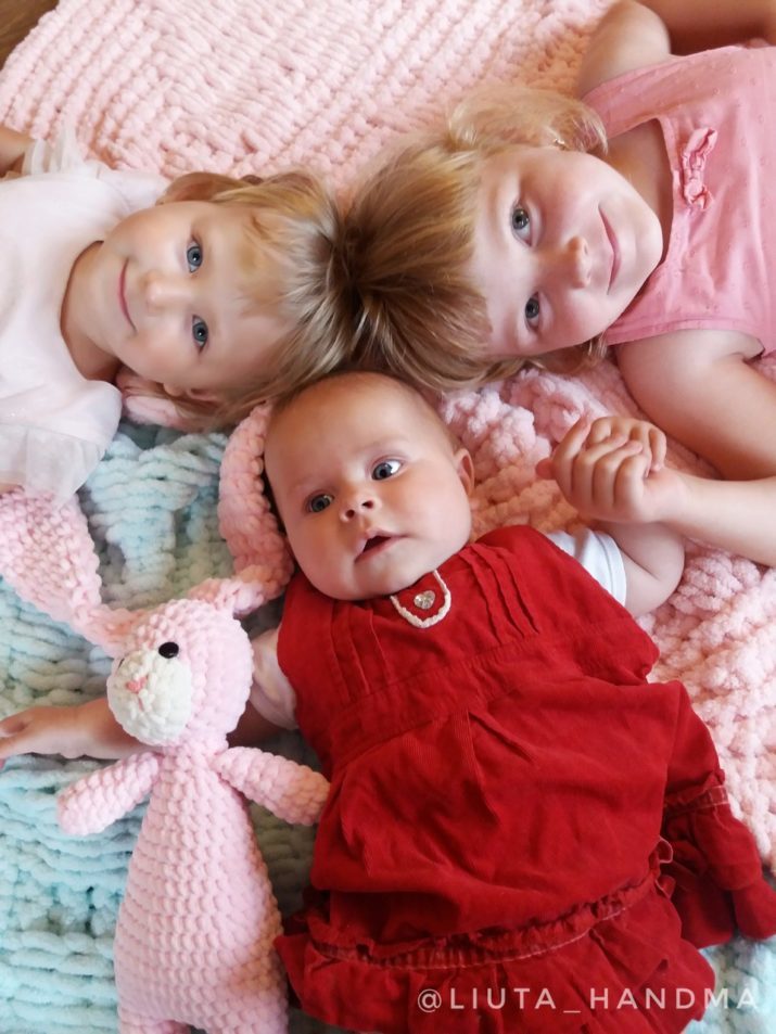 Плюшевий в'язаний плед рожевого та бірюзового кольору і діти з іграшкою 