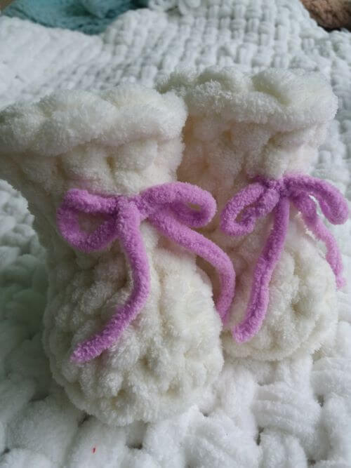 Плюшеві пінетки білосніжного кольору з шнурками фіолетового кольору ручного в'язання для немовляти